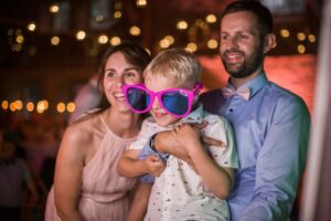 Kind und Eltern mit pinker Partybrille vor der Boxtastisch.de Fotobox
